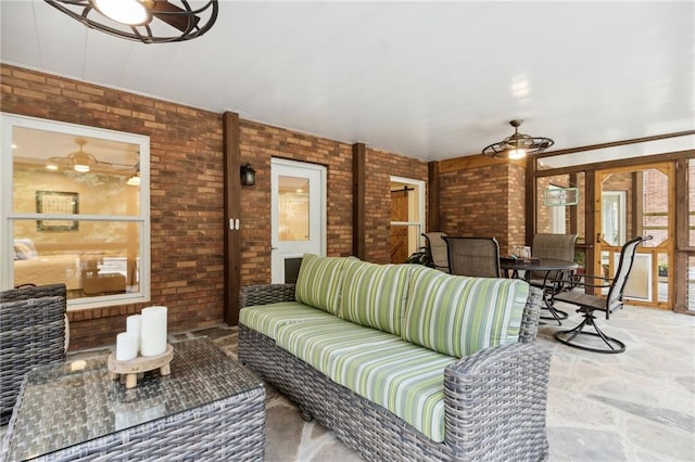 living room featuring ceiling fan and brick wall