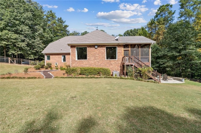 view of front of home featuring a sunroom, a front lawn, and central air condition unit