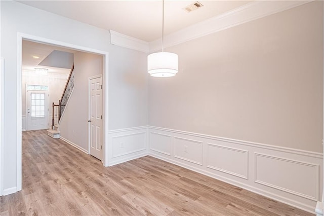 empty room with crown molding and light wood-type flooring