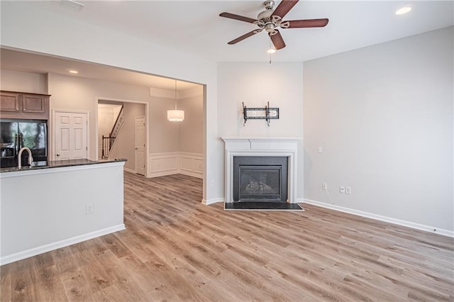 unfurnished living room with ceiling fan, light hardwood / wood-style floors, and sink