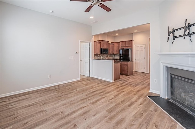 kitchen with sink, light hardwood / wood-style flooring, ceiling fan, decorative backsplash, and black fridge with ice dispenser