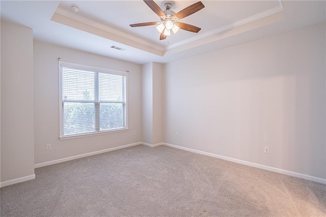 carpeted empty room with a raised ceiling, ceiling fan, and ornamental molding