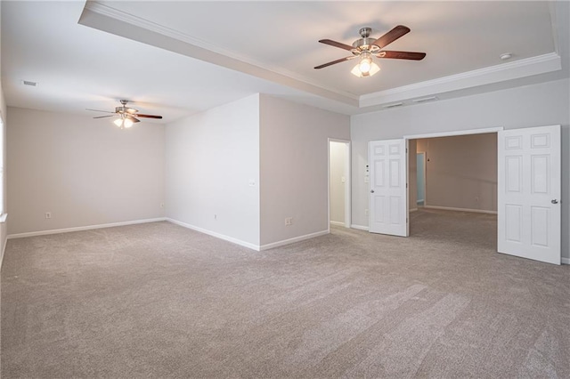 empty room with a tray ceiling, crown molding, and ceiling fan