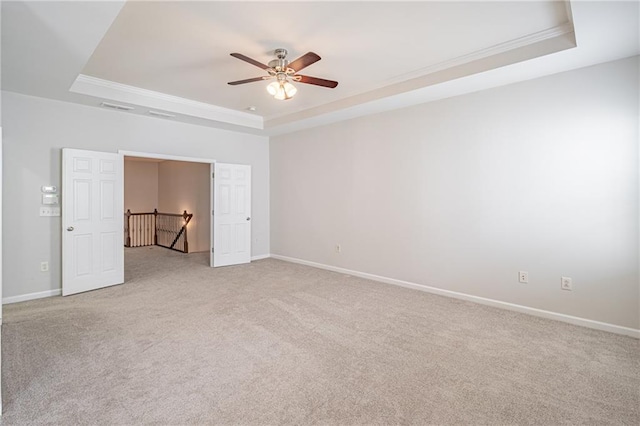 carpeted spare room with a raised ceiling, crown molding, and ceiling fan