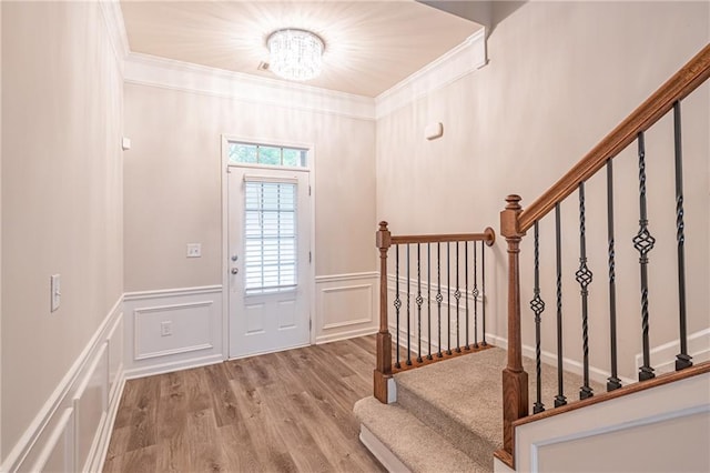 entrance foyer featuring crown molding, light hardwood / wood-style flooring, and a notable chandelier