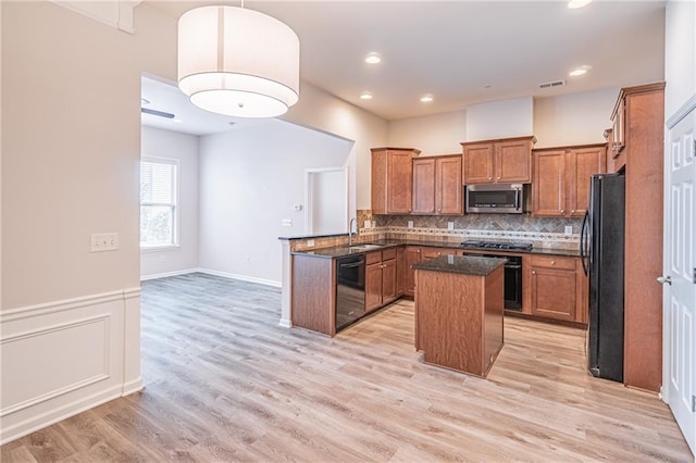 kitchen featuring black appliances, a kitchen island, kitchen peninsula, and light hardwood / wood-style flooring