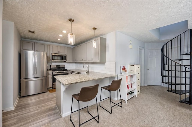 2507 Albion Farm Way, Duluth, GA 30097 - kitchen with appliances with stainless steel finishes, a sink, a textured ceiling, a peninsula, and a breakfast bar