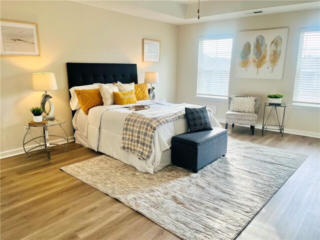 bedroom with visible vents, baseboards, and wood finished floors