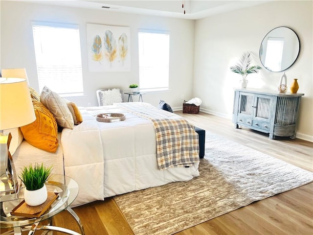 bedroom with visible vents, baseboards, and wood finished floors