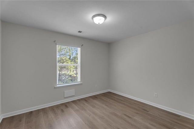 unfurnished room featuring visible vents, baseboards, and wood finished floors