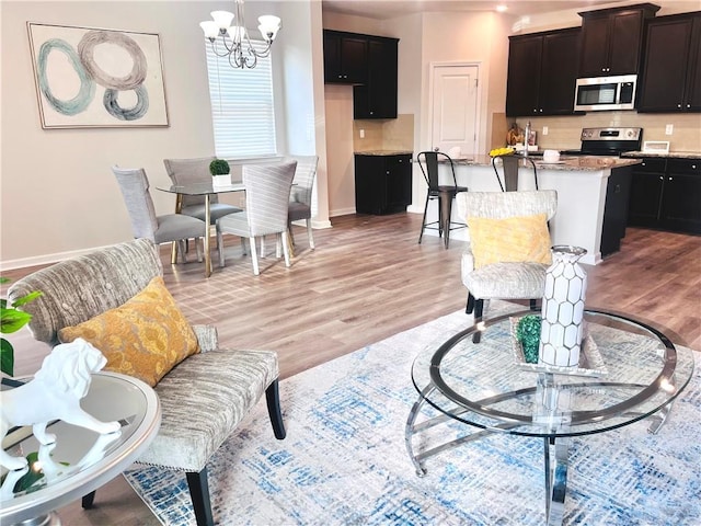 interior space featuring light wood-type flooring, baseboards, and a chandelier