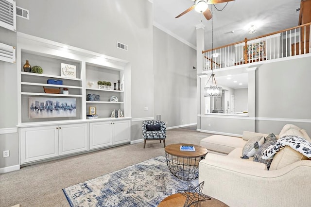 living room featuring ornamental molding, carpet flooring, a towering ceiling, and ceiling fan with notable chandelier