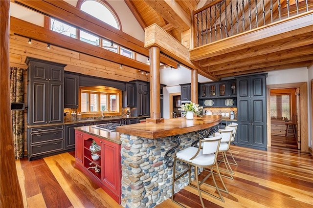 kitchen with a kitchen island, ornate columns, open shelves, beam ceiling, and decorative backsplash