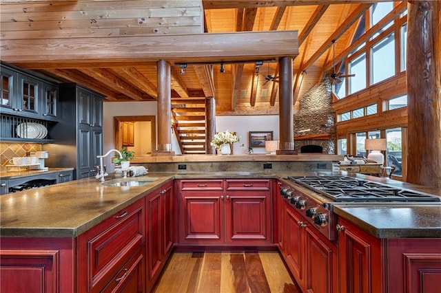 kitchen featuring a sink, stainless steel gas stovetop, reddish brown cabinets, beamed ceiling, and wooden ceiling