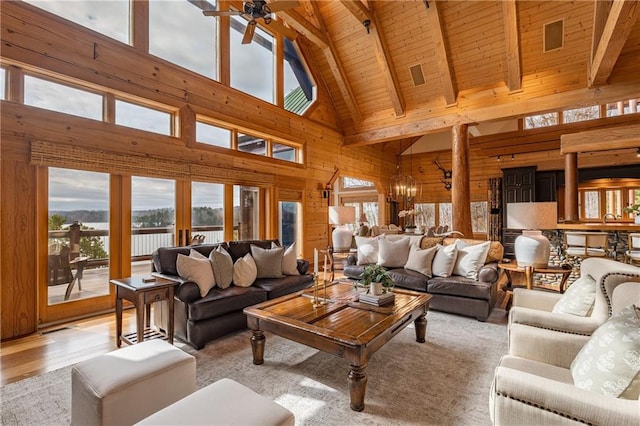 living room featuring wood walls, high vaulted ceiling, and plenty of natural light