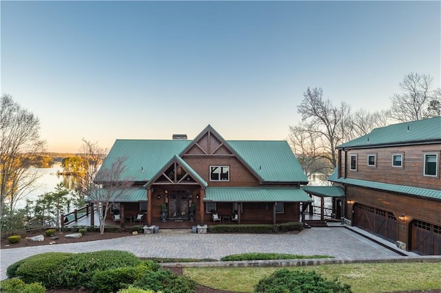 view of front of home featuring a chimney, a porch, metal roof, and a garage