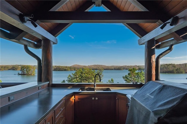 view of patio with a sink, grilling area, a water view, and an outdoor kitchen