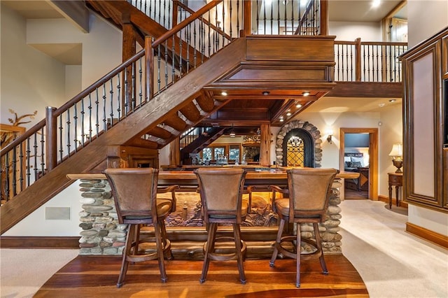 bar with indoor bar, stairway, baseboards, and a high ceiling