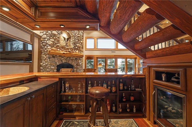 wine room with beverage cooler, a stone fireplace, and wood finished floors