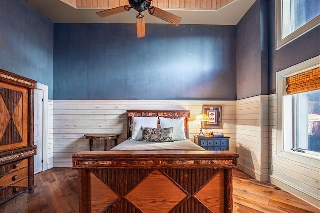 bedroom featuring multiple windows, wooden walls, and hardwood / wood-style flooring
