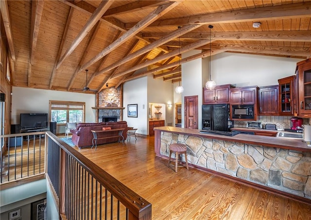 kitchen featuring a stone fireplace, wood ceiling, open floor plan, high vaulted ceiling, and black appliances