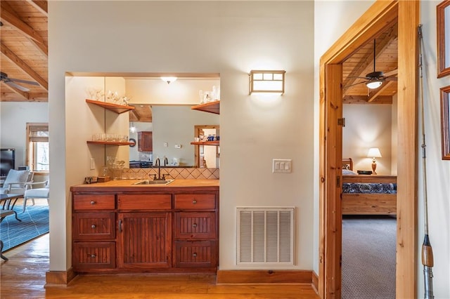 hall featuring a sink, visible vents, wooden ceiling, light wood finished floors, and beamed ceiling