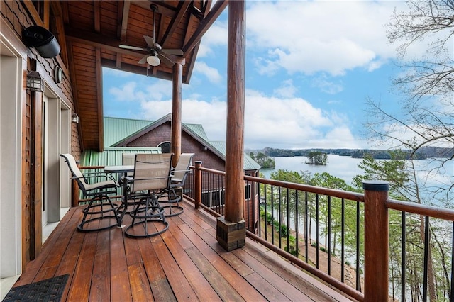 wooden terrace featuring a water view, outdoor dining area, and a ceiling fan