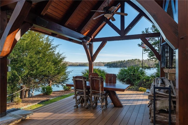 wooden terrace with outdoor dining space, a gazebo, a water view, and a ceiling fan