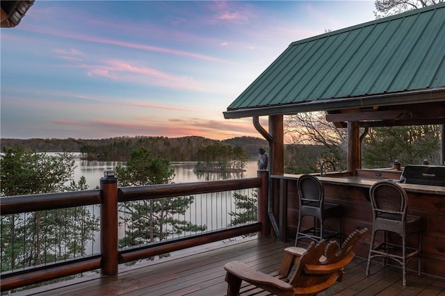 wooden deck with area for grilling, a water view, and outdoor dry bar