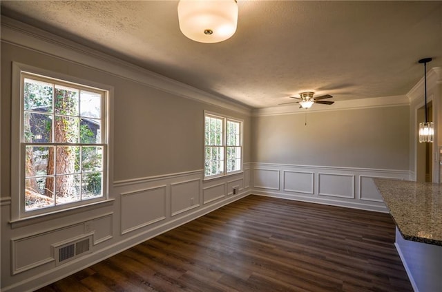 unfurnished dining area with ornamental molding, dark wood-type flooring, a healthy amount of sunlight, and ceiling fan