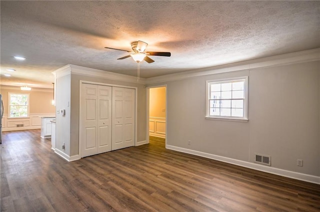 unfurnished bedroom featuring a textured ceiling, dark hardwood / wood-style flooring, a closet, ceiling fan, and ornamental molding