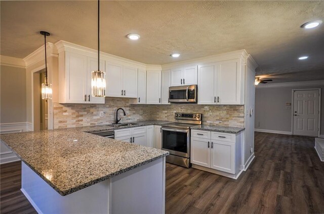 kitchen featuring appliances with stainless steel finishes, sink, hanging light fixtures, white cabinets, and dark wood-type flooring