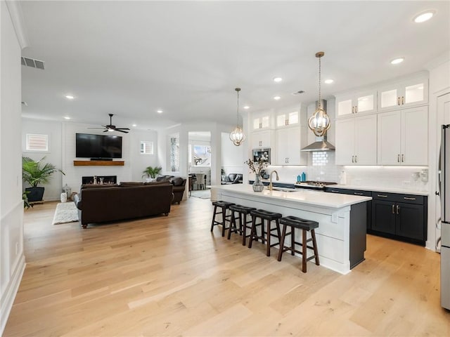 kitchen with sink, a breakfast bar, a kitchen island with sink, hanging light fixtures, and white cabinetry