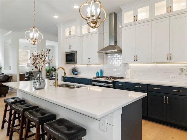 kitchen featuring built in microwave, white cabinetry, a kitchen island with sink, and wall chimney exhaust hood