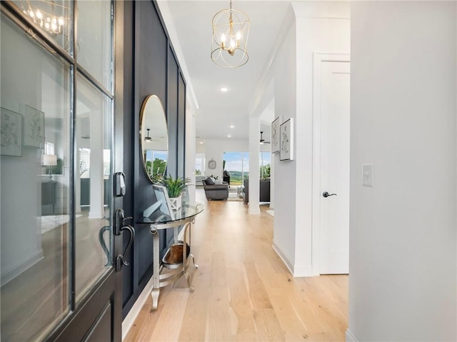 hall featuring an inviting chandelier and light wood-type flooring