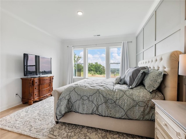 bedroom with ornamental molding and light hardwood / wood-style flooring