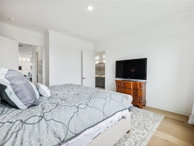 bedroom with crown molding, light hardwood / wood-style floors, and ensuite bathroom