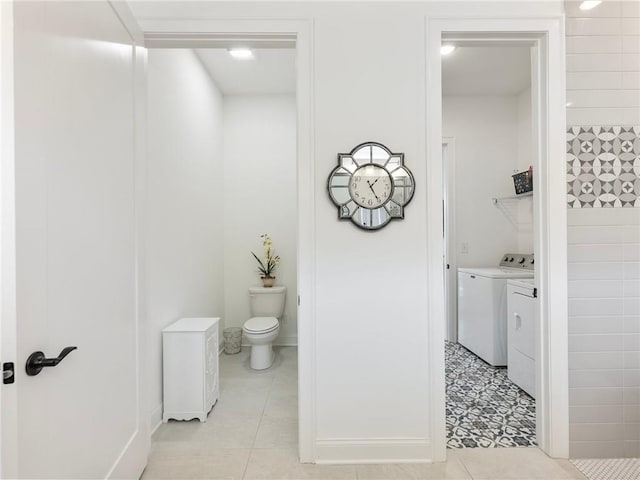 bathroom with independent washer and dryer, tile patterned floors, and toilet