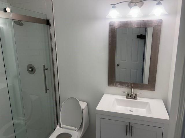 bathroom featuring vanity, toilet, and a shower with shower door