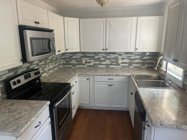 kitchen with dark hardwood / wood-style floors, tasteful backsplash, sink, white cabinets, and stainless steel appliances