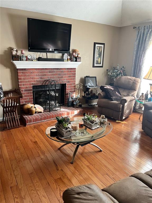 living room featuring hardwood / wood-style flooring, a fireplace, and vaulted ceiling