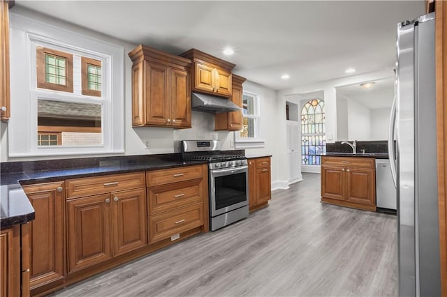 kitchen with dark stone counters, sink, light hardwood / wood-style floors, and appliances with stainless steel finishes