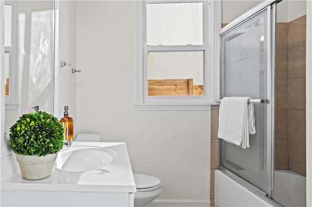 full bathroom featuring vanity, bath / shower combo with glass door, and toilet