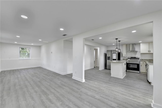 kitchen with wall chimney range hood, a kitchen island, open floor plan, and stainless steel appliances