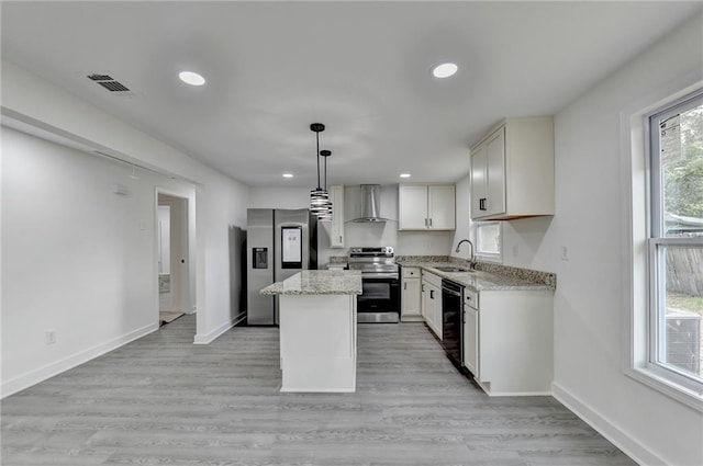 kitchen featuring baseboards, stainless steel appliances, a kitchen island, a sink, and wall chimney range hood