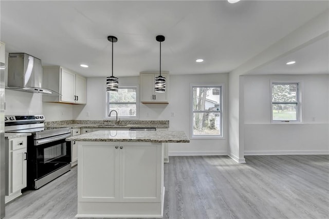 kitchen featuring plenty of natural light, electric stove, a sink, wall chimney range hood, and a center island