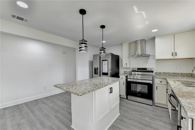 kitchen with stainless steel appliances, a kitchen island, light wood-style floors, visible vents, and wall chimney exhaust hood
