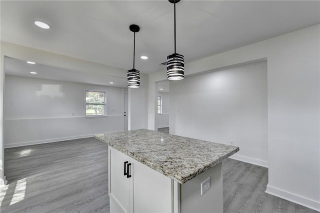 kitchen with baseboards, light stone countertops, a kitchen island, dark wood-type flooring, and hanging light fixtures