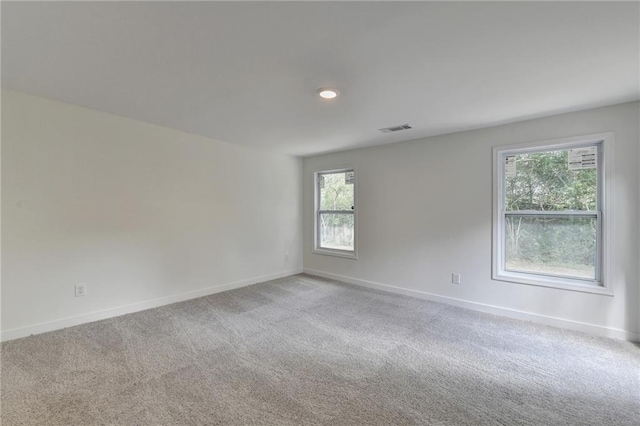 empty room with baseboards, visible vents, and carpet