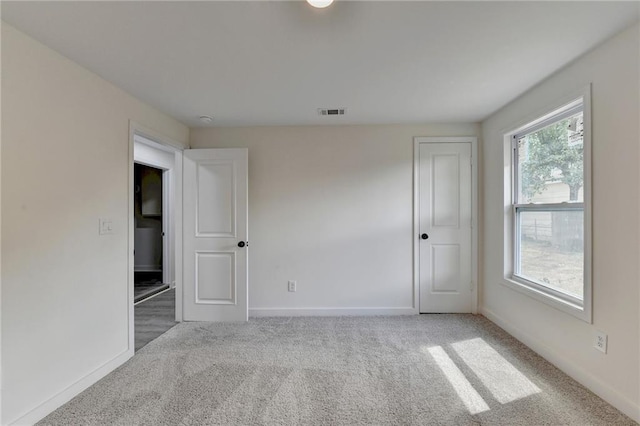 empty room featuring baseboards, carpet floors, and visible vents